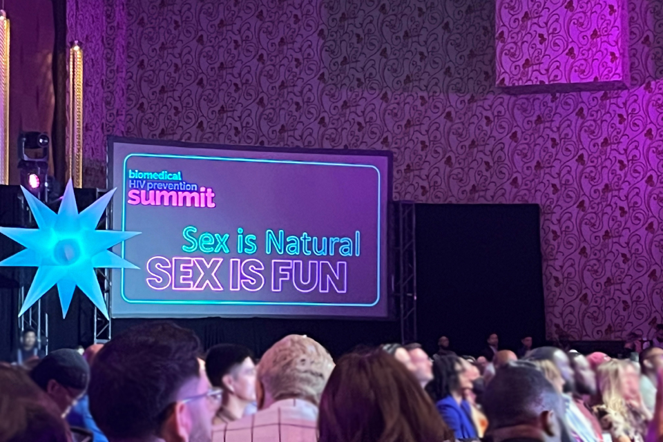 Crowd at 2023 Biomedical HIV Prevention Summit and screen that reads &quot;Sex is Natural, Sex is Fun&quot;.