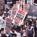 People at a march holding signs that say "Silence = Death" and "AIDS: WHERE IS YOUR RAGE? ACT UP"
