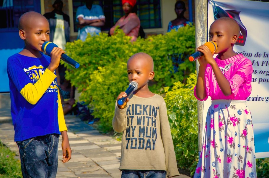 Three children singing with microphones outside.