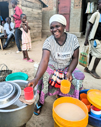 Woman sitting down with pots of porridge to sell.
