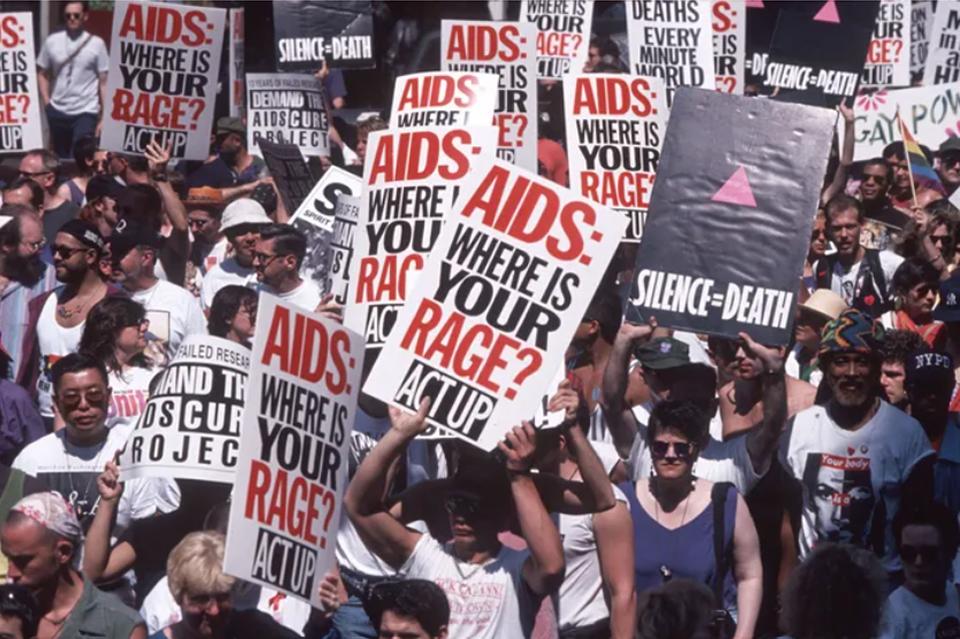 People at a march holding signs that say &quot;Silence = Death&quot; and &quot;AIDS: WHERE IS YOUR RAGE? ACT UP&quot;