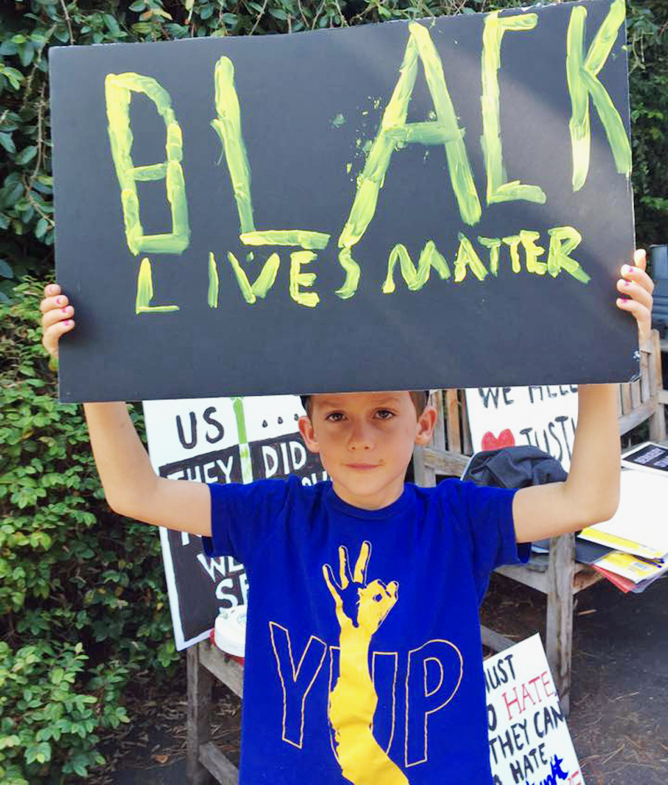 Young boy holding a sign the reads "BLACK LIVES MATTER".