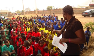 The Well Project Global Ambassador, Bose Olotu, speaking to a large group of students.