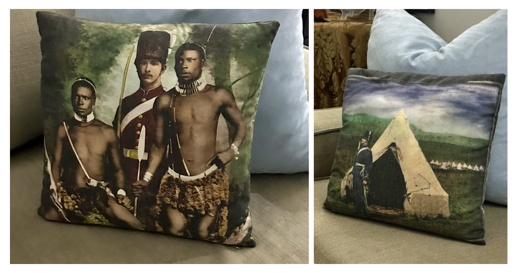 Pillows depicting white men in uniform and Black wearing traditional clothing on bottom and necklaces.