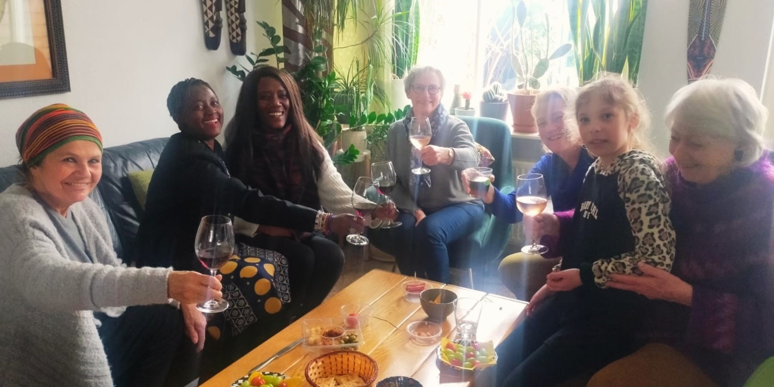 Eliane and others sitting around a table with glasses of wine.