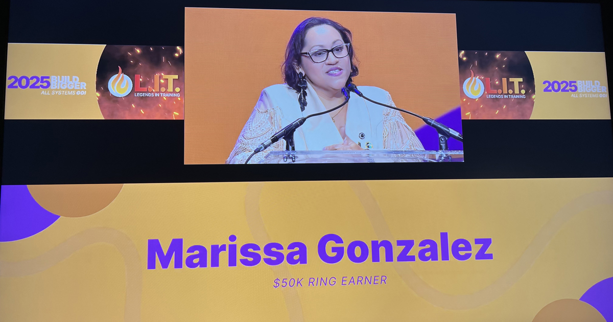 Marissa Gonzalez on a stage with screens behind her showing her.