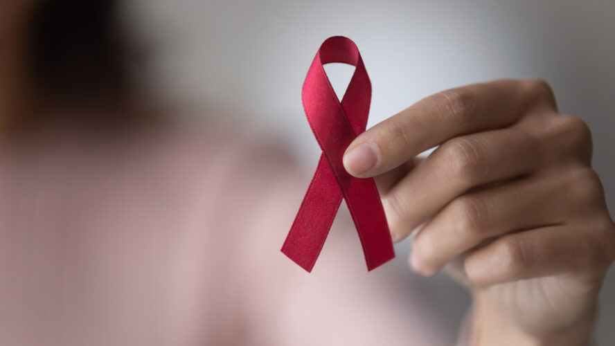 Woman's hand holding a red ribbon.