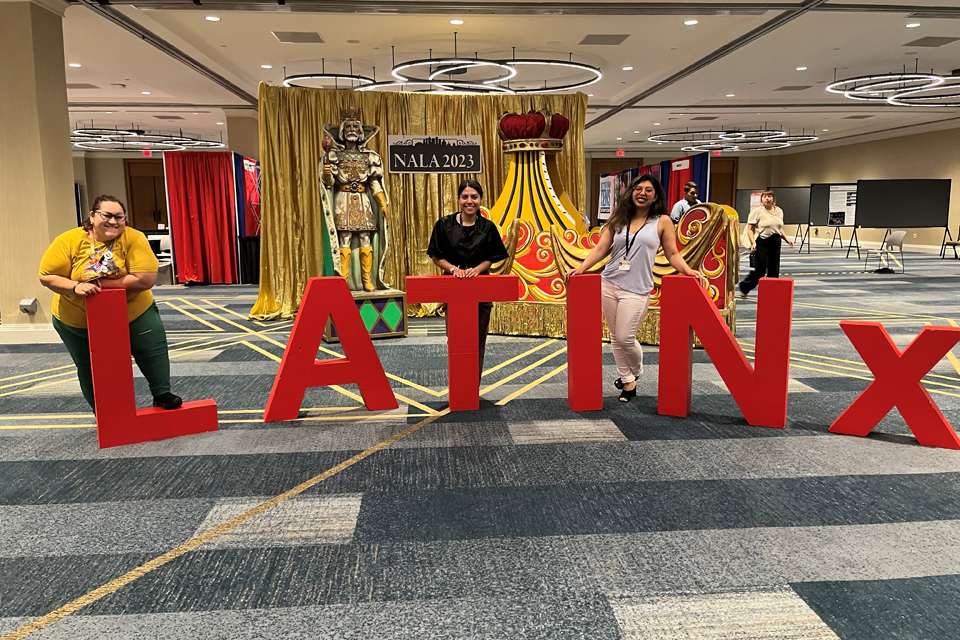 Marissa Gonzalez y otras parados junto a un cartel que dice &quot;LATINX&quot;.