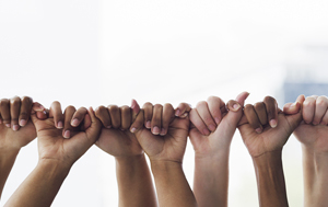 Hands of various skin tones linking pinky to thumb in a row.