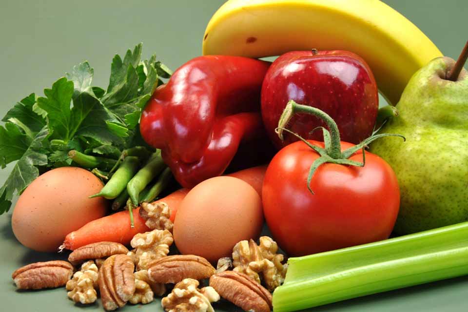 Frutas, verduras, nueces y huevos sobre una mesa.