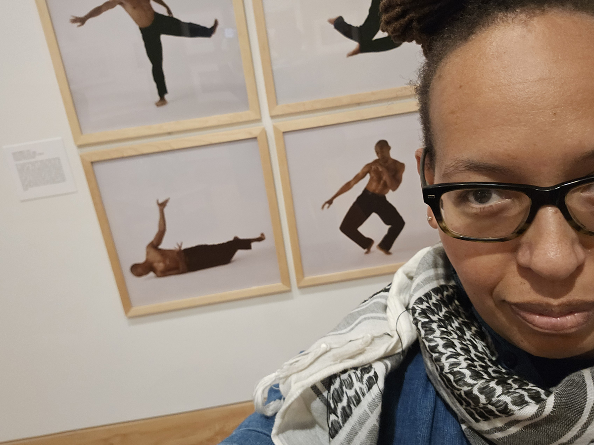 Olivia G. Ford standing in front of photos of Bill T. Jones at the Carle Museum.