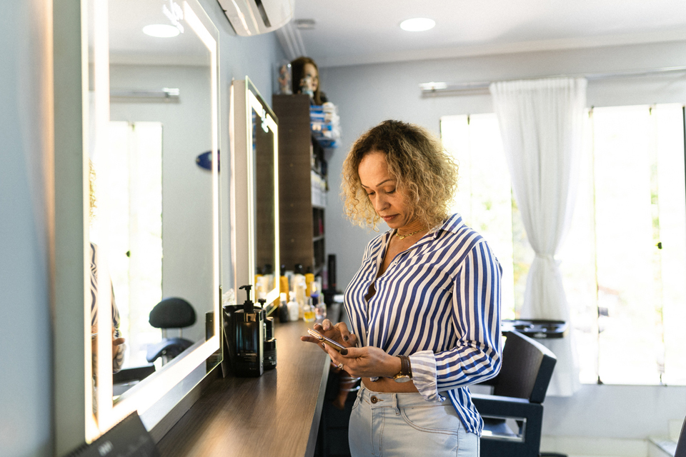 Woman of trans experience using smartphone in beauty salon.