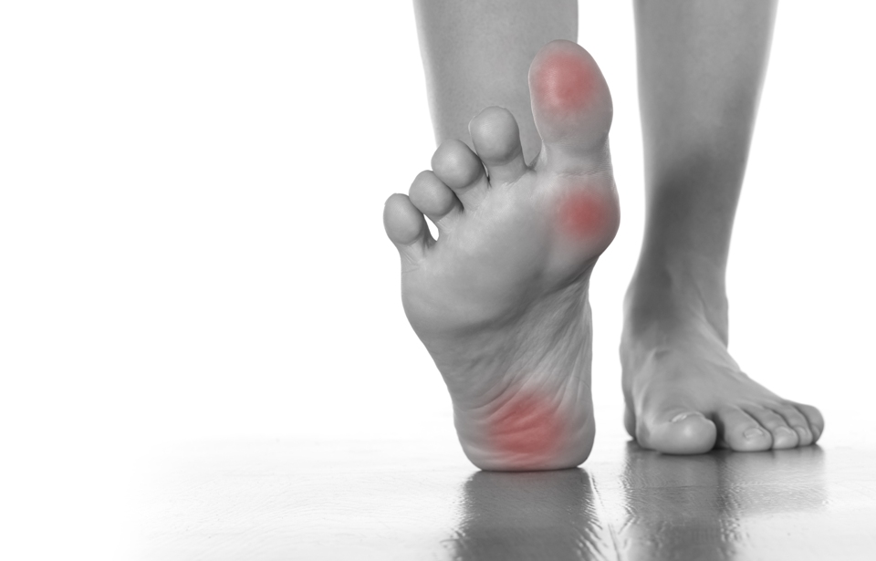 Person's feet on floor, one flat on ground, the other flexed, showing red areas on toe, ball & heel.