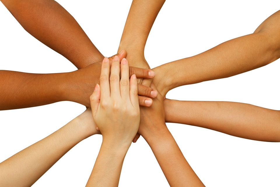 Several hands of varying skin tones coming in from a circle, overlapping at the center. 