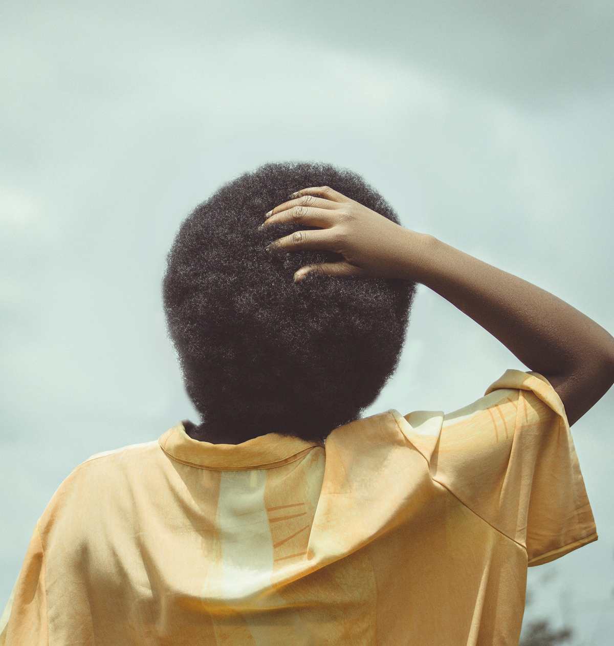 Back view of a woman with her hand on the back of her head.