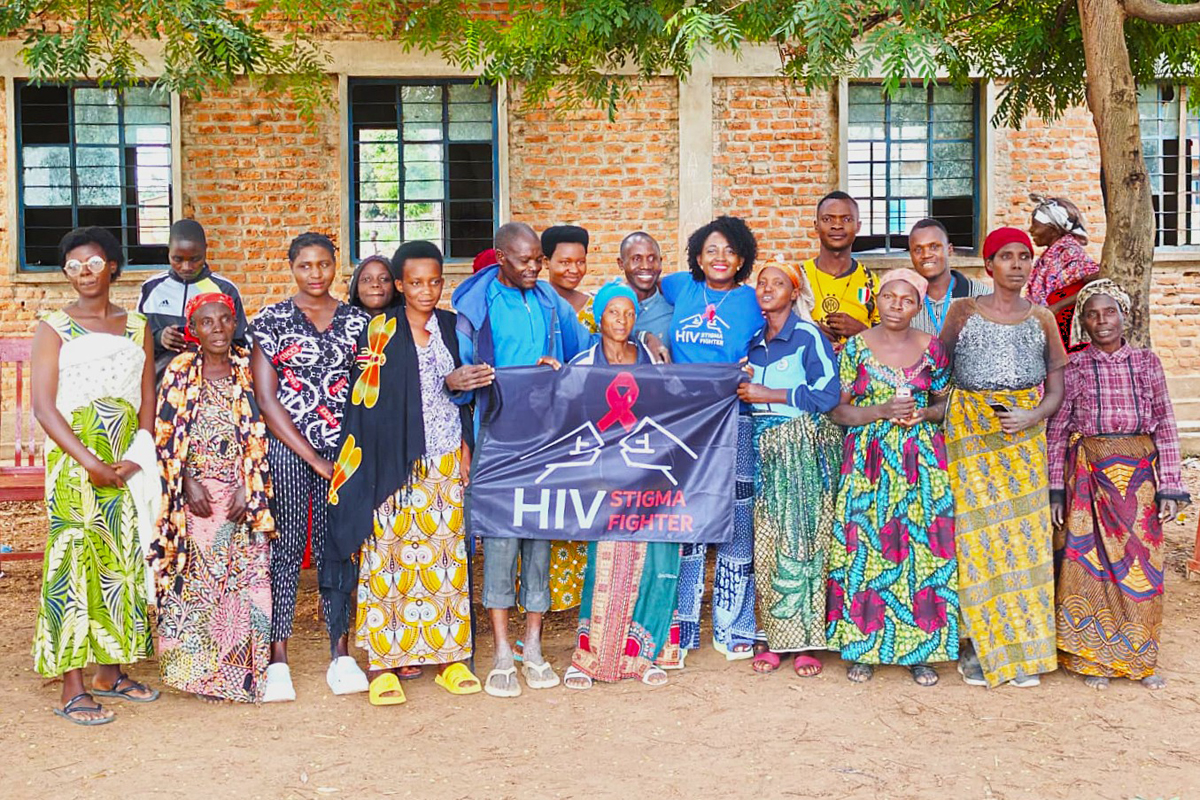 People standing in a row, some holding a sign that reads, "HIV Stigma Fighter".