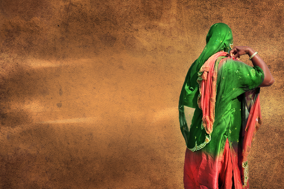 Espalda de mujer en sari frente a una pared.
