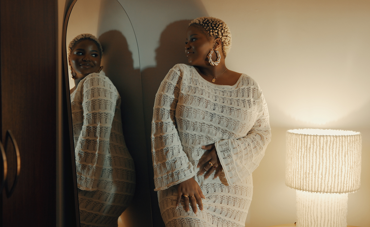 Woman in a white dress looking at herself in the mirror and smiling.