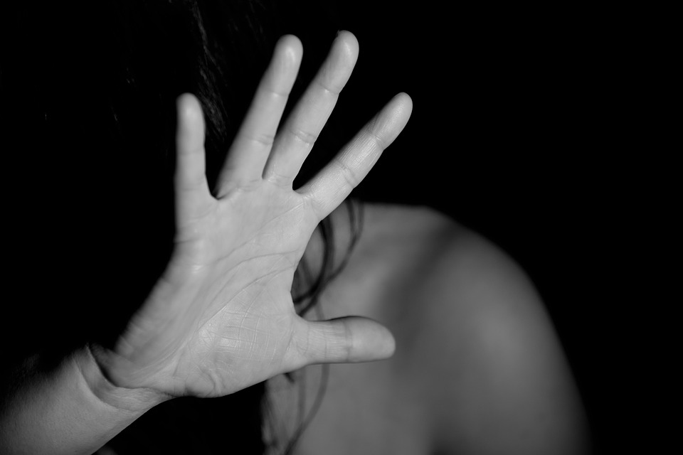 Woman with bare shoulders raising her hand to cover her face.