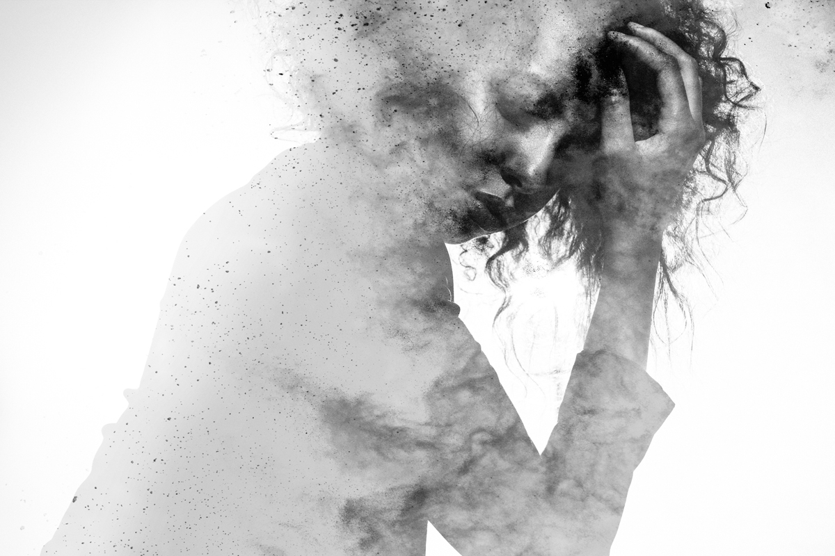 Woman with eyes closed and hand on head double exposed with a monochromatic paint splatter effect.