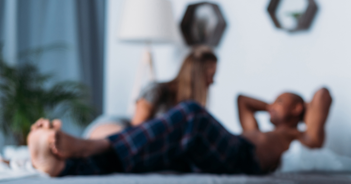 Blurry photo of two people lying on bed talking.