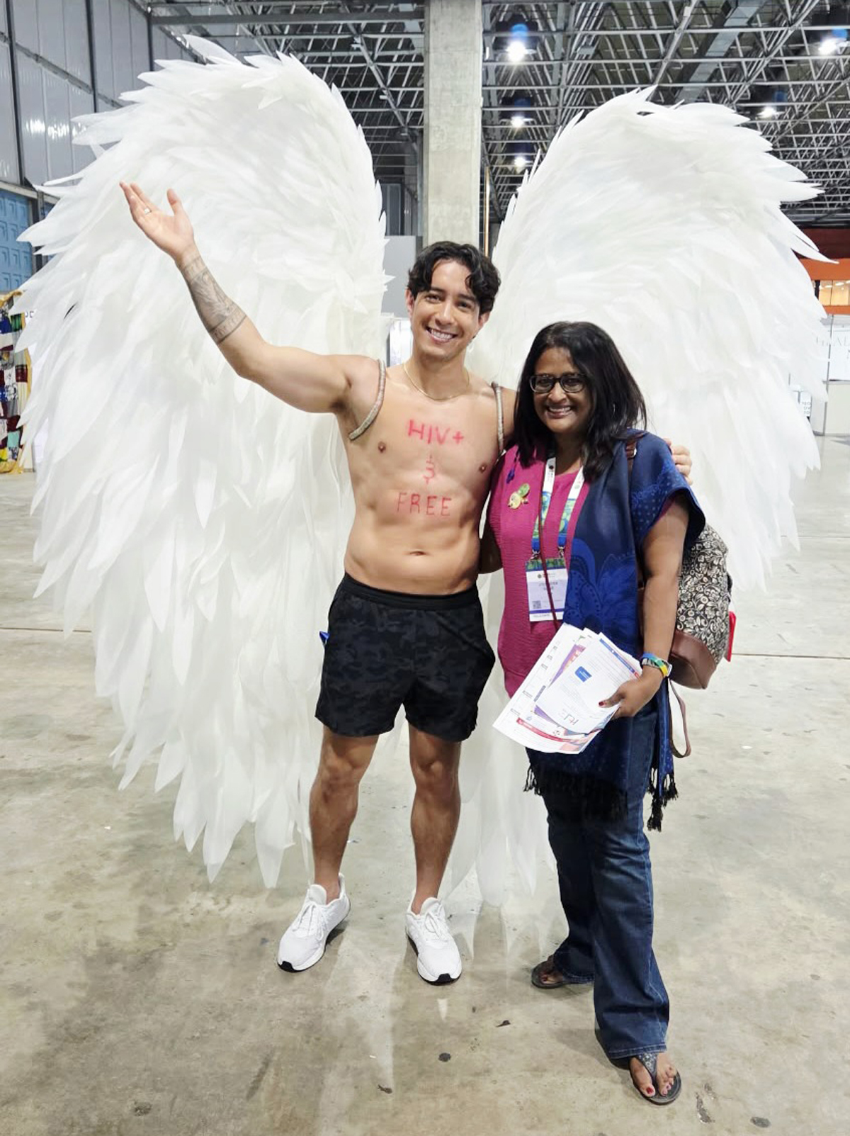 Jo and someone with angel wings whose body has the words "HIV+ &amp; FREE" written on it.