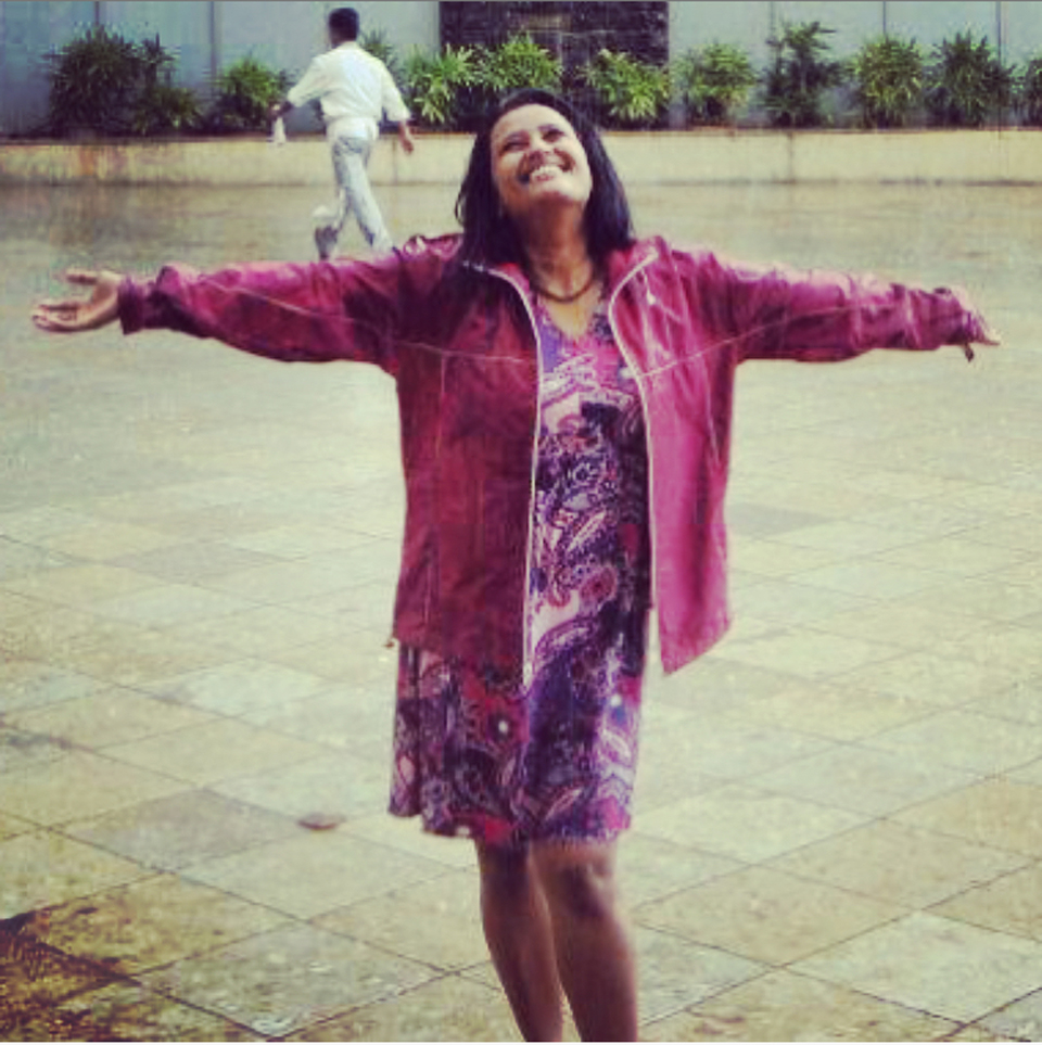 JoDha, standing in public square, arms outstretched, smiling.