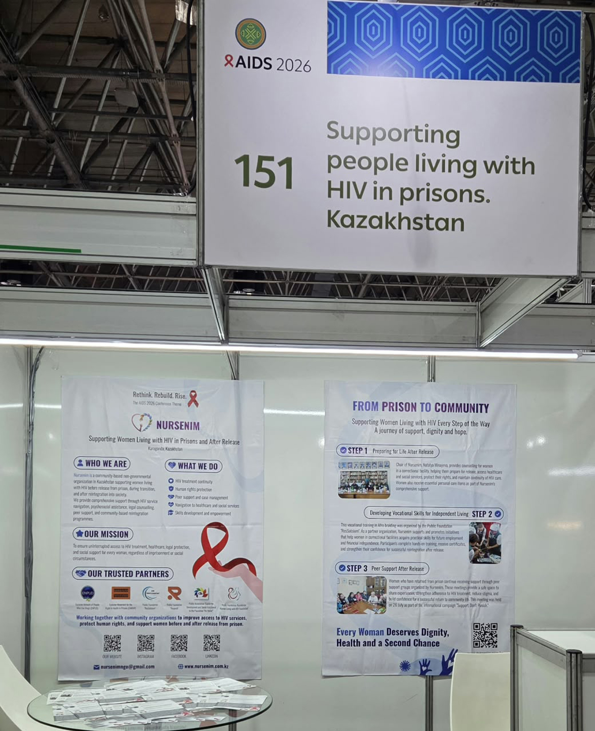 Booth 151 at AIDS 2021 with posters up and a sign reading "Supporting people living with HIV in prisons, Kazakhstan".