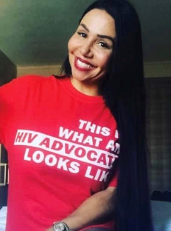 Maria Mejia, smiling, in shirt that reads "This is what an HIV advocate looks like".