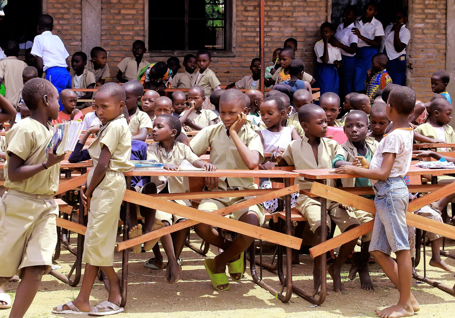 Many school children standing and sitting.