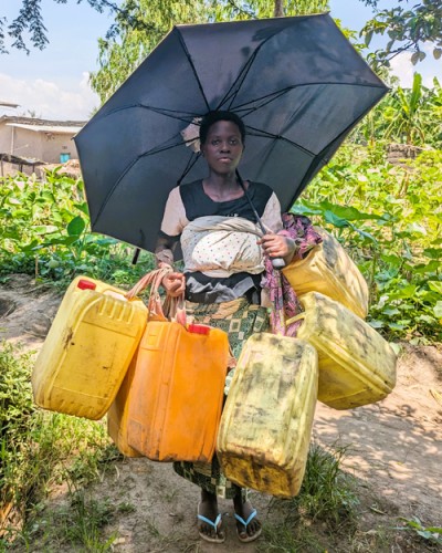 Woman with umbrella and containers for gathering water.