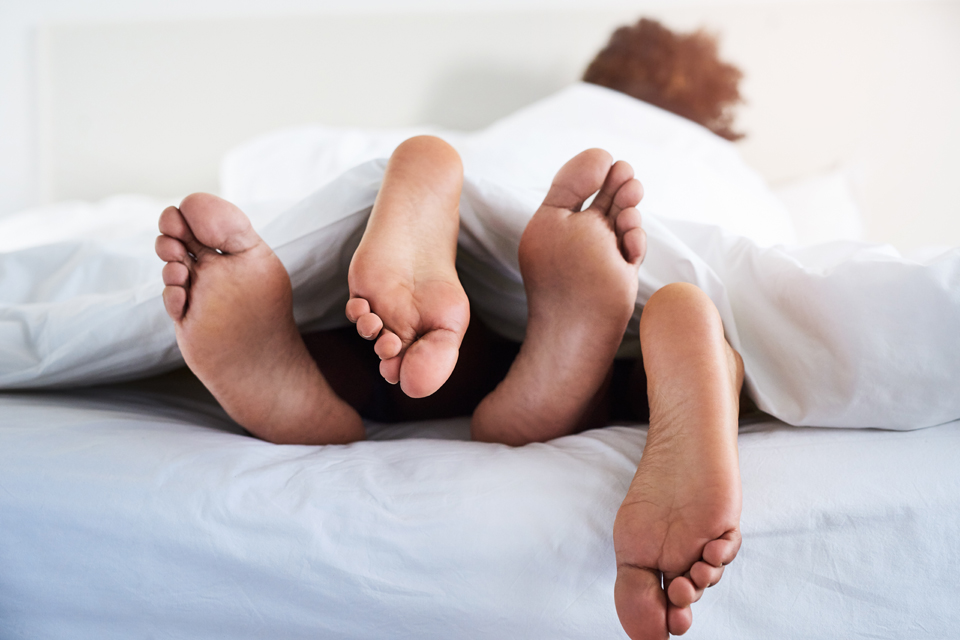 Two people's feet poking out from under the sheets.