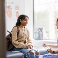 Woman and health care professional smiling and talking in medical office.