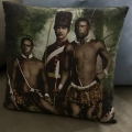 Pillow depicting white man in uniform and two Black men in traditional clothing on bottom and necklaces.
