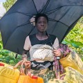 Woman with umbrella and containers for gathering water.