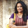 Jyoti Dhawale standing in front of wall with arms crossed.