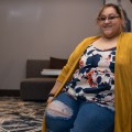 Marissa Gonzalez, sitting on a sofa, smiling.