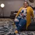 Marissa Gonzalez, sitting on a sofa, smiling.