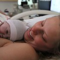 Heather O'Connor in hospital bed, smiling, holding newborn baby on her chest.