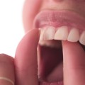 Close up of person opening their mouth and flossing their teeth.