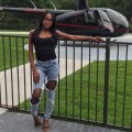 Ieshia Scott, outside, leaning on a metal fence, with a small aircraft behind it.