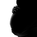 Silhouette of a pregnant woman's belly, her hands cradling it.