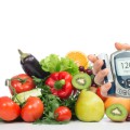 Fruits, vegetables, and a hand holding a blood sugar monitor.