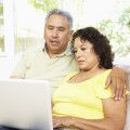 Una pareja mayor sentada en un sofá mirando una laptop juntos.