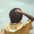 Back view of a woman with her hand on the back of her head.