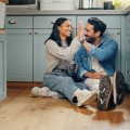 Una pareja sentada en el suelo de la cocina chocando los cinco.