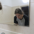 Person at bathroom sink with mirror in front of them.