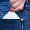 Hand taking a condom out of a back pocket of jeans.