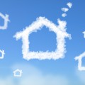 Blue sky with white clouds shaped like houses. 