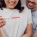 A couple, smiling, looking at the results of a home pregnancy test.